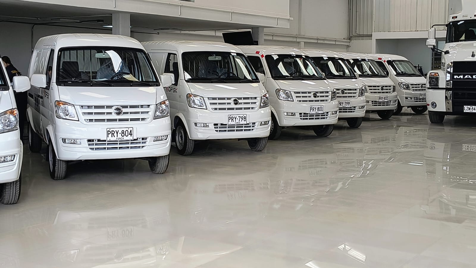 [Asesor mostrando inventario de minivans en sala de venta]